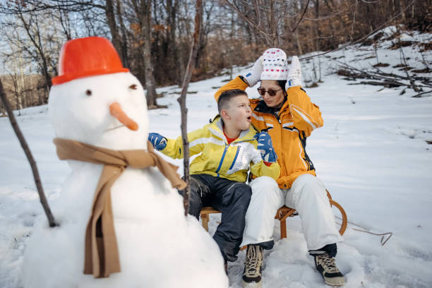 Boy having fun on snowy mountain together with his mother