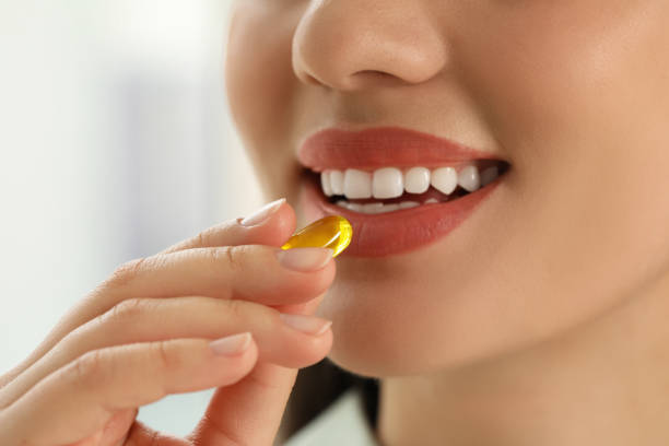 istock Young woman taking dietary supplement pill on blurred background, closeup 1470803165