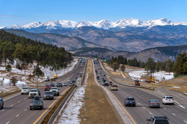 highway and snow peaks - ein sonniger wintertag mit blick auf den belebten interstate highway i-70 mit schneebedeckten hohen gipfeln der kontinentalen wasserscheide, die im westen aufragen. denver, colorado, usa. - denver colorado colorado winter snow stock-fotos und bilder