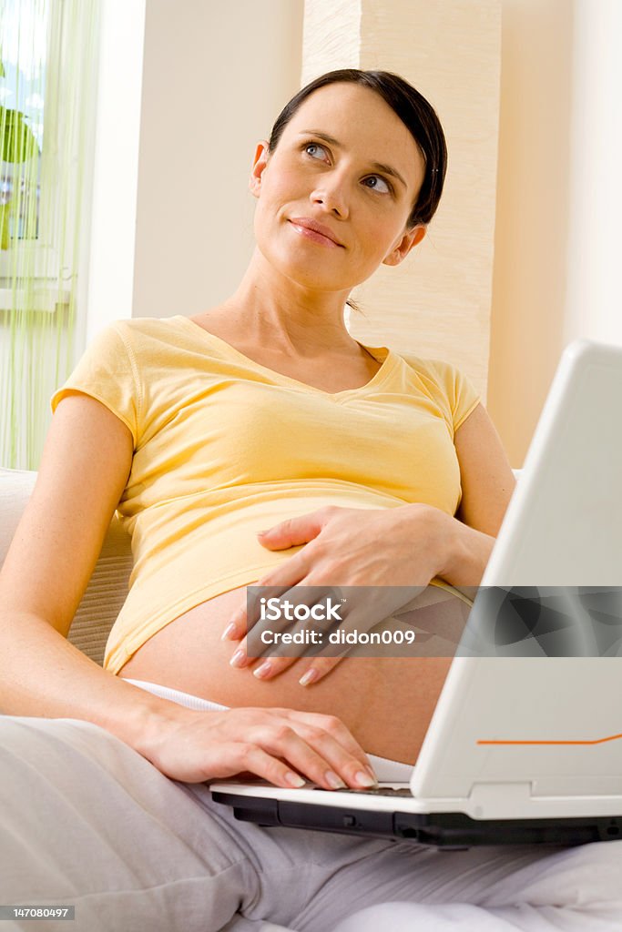 Young pregnant woman with laptop Pregnant woman using laptop Abdomen Stock Photo