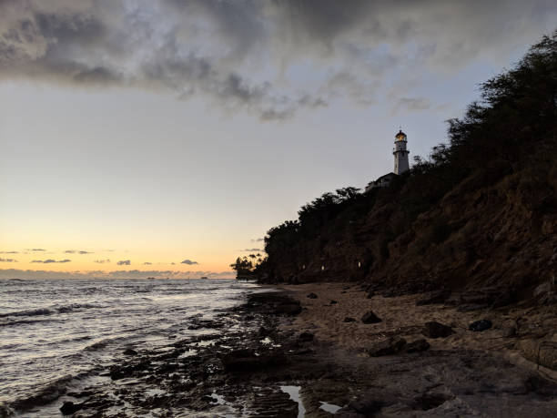 istock Diamond Head Lighthouse: A Stunning Sunset on Oahu's Rocky Shore 1470806408