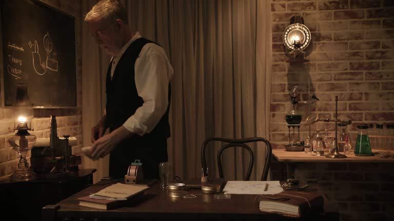 Edison drawing the filament on a blackboard and sitting