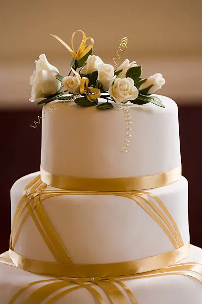 Top of Wedding Cake Decorated with Roses and Gold Ribbon