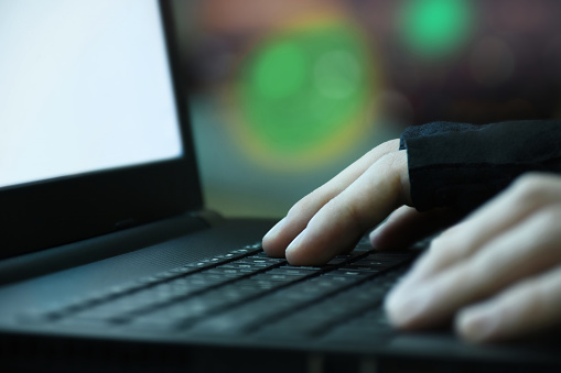 Computer hacker using laptop. Hacker hands on the laptop keyboard at late night, Hacker typing on laptop