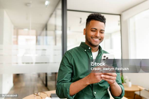 Young Indian Male Employee Freelancer Businessman Stands With A Smartphone In Hand Stock Photo - Download Image Now