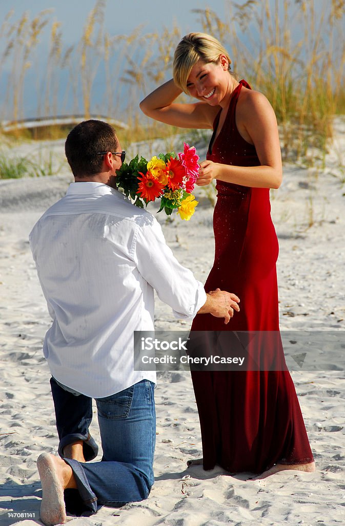 Man offering woman flowers Man down on one knee offering bouquet to woman Engagement Stock Photo