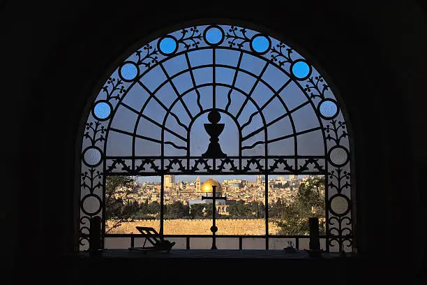 Old city of Jerusalem viewed through decorative arched window of Dominoes Flevit church, Israel.