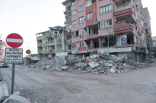 Hatay, Turkey February 15, 2023\nTraffic sign and destroyed buildings. Many buildings were destroyed after the great earthquake. There is no one in the picture. Everywhere is bad.