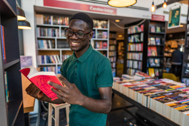 istock Young man reading book in the library 1470814960