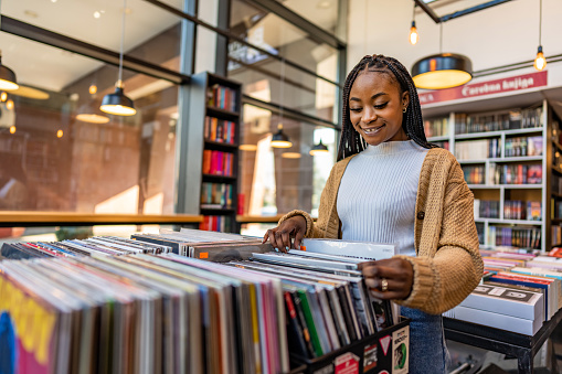 Young beautiful woman in a vinyl store choosing records.
