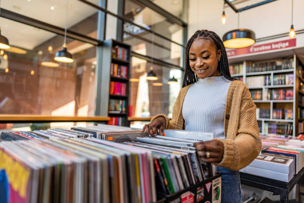 young beautiful woman in a vinyl store choosing records. - library young adult bookstore people imagens e fotografias de stock