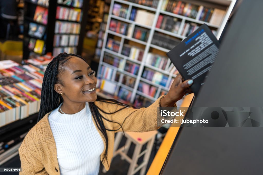 Young librarian picking book from bookshelf Bookshelf Stock Photo