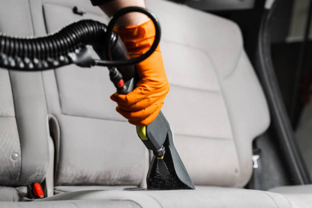 istock Close-up dry cleaning extractor machine is spraying water and detergent on textile seat inside car. Car dry cleaner is using extraction machine for removing stains and dirt from textile seats. 1470818520