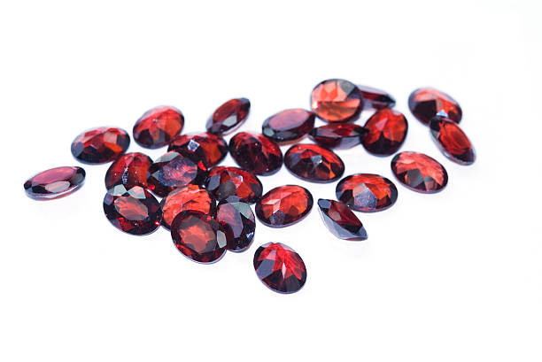 A collection of red garnet stones in a white background Garnets isolated on white background. Shallow depth of field with the nearest stones in focus. garnet stock pictures, royalty-free photos & images