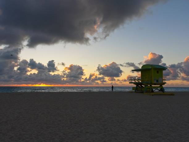 istock Wide angle view as sun breaks over the Atlantic with a lifeguard hut in view and silhouette of a man 1470820166