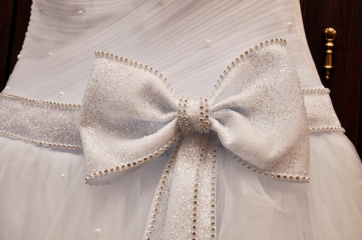 A large white bow on the belt of the wedding dress. close-up