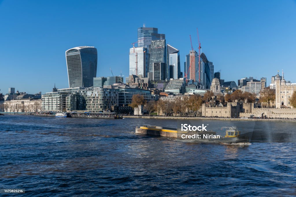 A tugboat on the Thames in central London A tugboat pulling a barge on the Thames, The City skyscrapers in the background on a beautiful sunny day. 20 Fenchurch Street Stock Photo