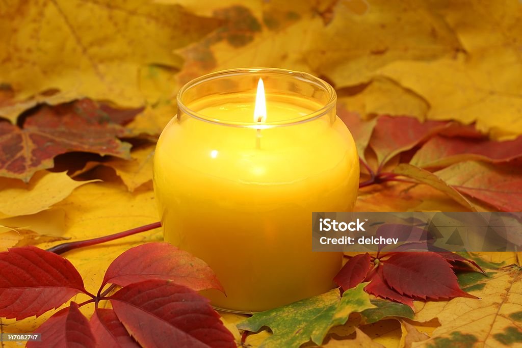 light of autumn big candle on floor of colored autumn leaves. Autumn Stock Photo