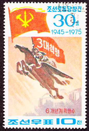 30th anniversary of the North Korean Workers Party.  North Koreans riding Chollima the flying horse.  The top flag is the flag of the Workers Party, with a hammer for the workers, a hoe for the peasants and a brush for the intellectuals.  Note the factories in the far background suggesting industrial power.- See lightbox for more