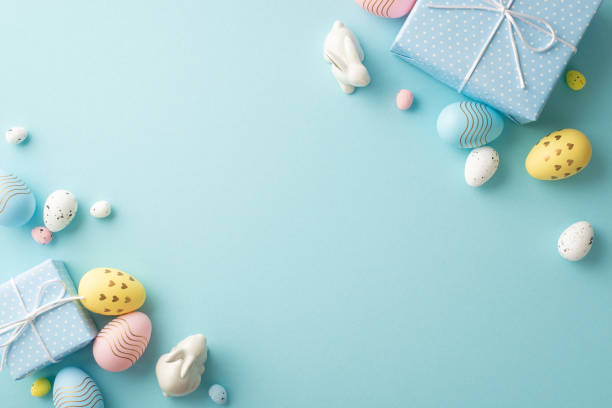Easter decorations concept. Top view photo of blue gift boxes colorful easter eggs and ceramic bunnies on isolated pastel blue background with blank space