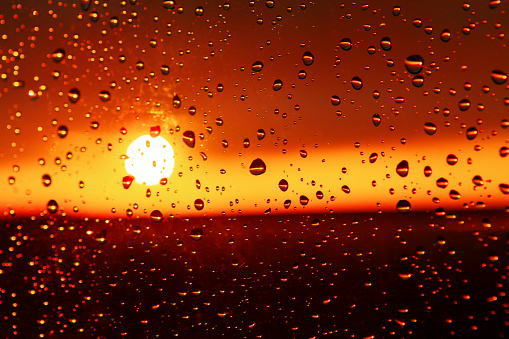 Water drops on the glass with sunset . Sunset in the rainy evening