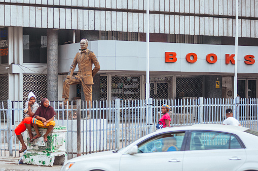 Lagos, Nigeria - Traffic scene with some people in street corner infront of bookshop.