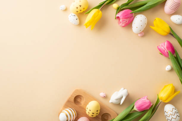 istock Easter celebration concept. Top view photo of colorful easter eggs ceramic easter bunny tulips and wooden egg holder on isolated pastel beige background with empty space 1470829776