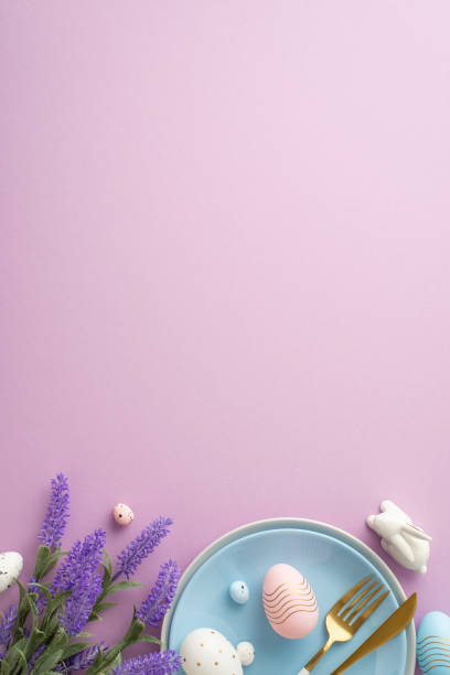istock Easter concept. Top view vertical photo of blue dish knife fork colorful easter eggs ceramic bunny and lavender flowers on isolated lilac background with copyspace 1470830358