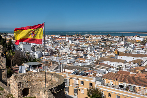 Aerial view of Sanlucar de Barrameda, with the flag of spain waving in the wind, in the province of Cadiz, Andalusia, Spain