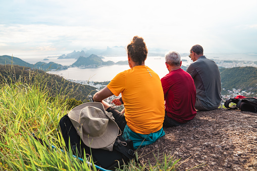 A group of three senior male hikers on top of a mountain enjoying the view of the sea