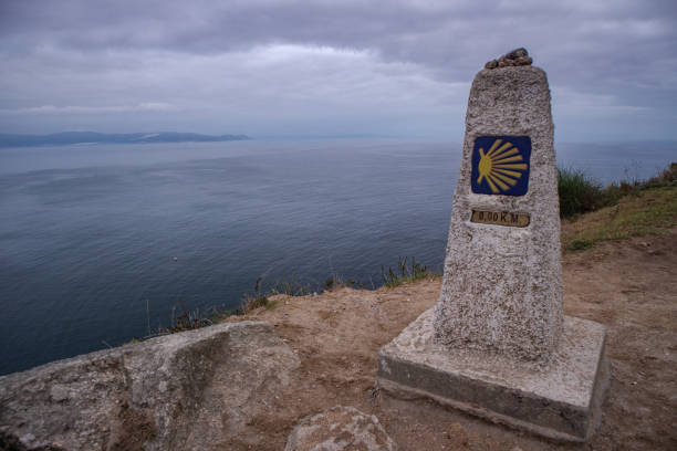 istock Milestone with shell symbol on cliff above sea 1470837469