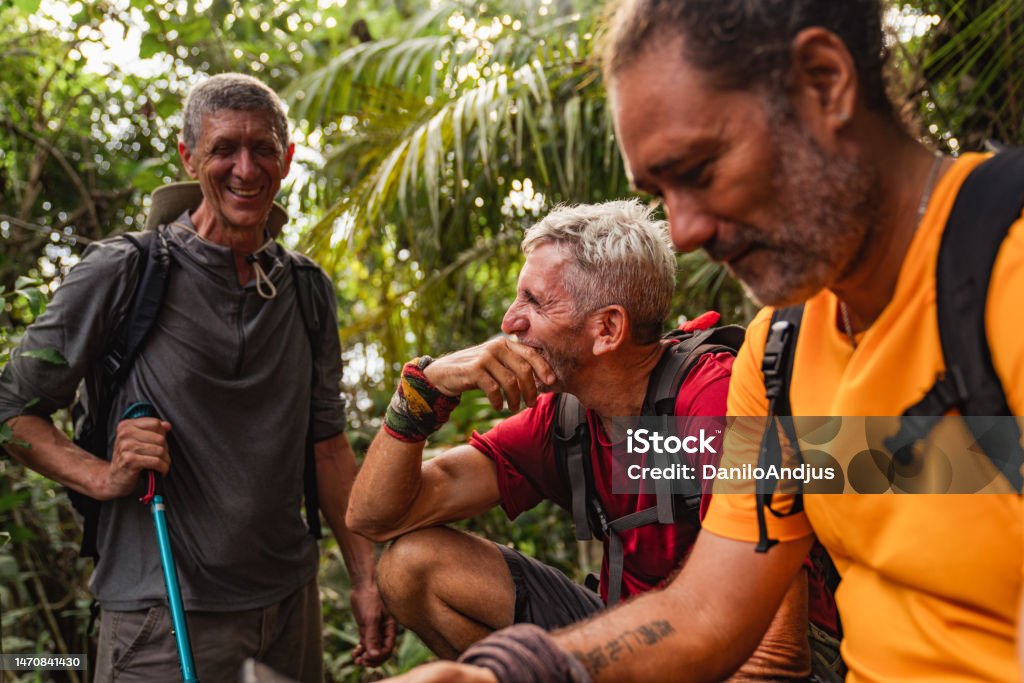 Three hikers having a break in wilderness. Close-up of a group of senior male hikers relaxing after a long hike Senior Adult Stock Photo