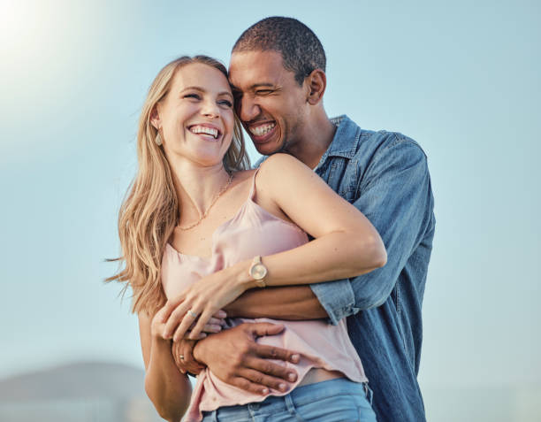 Love, diversity and couple hug on vacation, holiday or summer trip. Romantic, relax smile and happy man and woman hugging, embrace or cuddle, having fun and enjoying quality time together outdoors stock photo