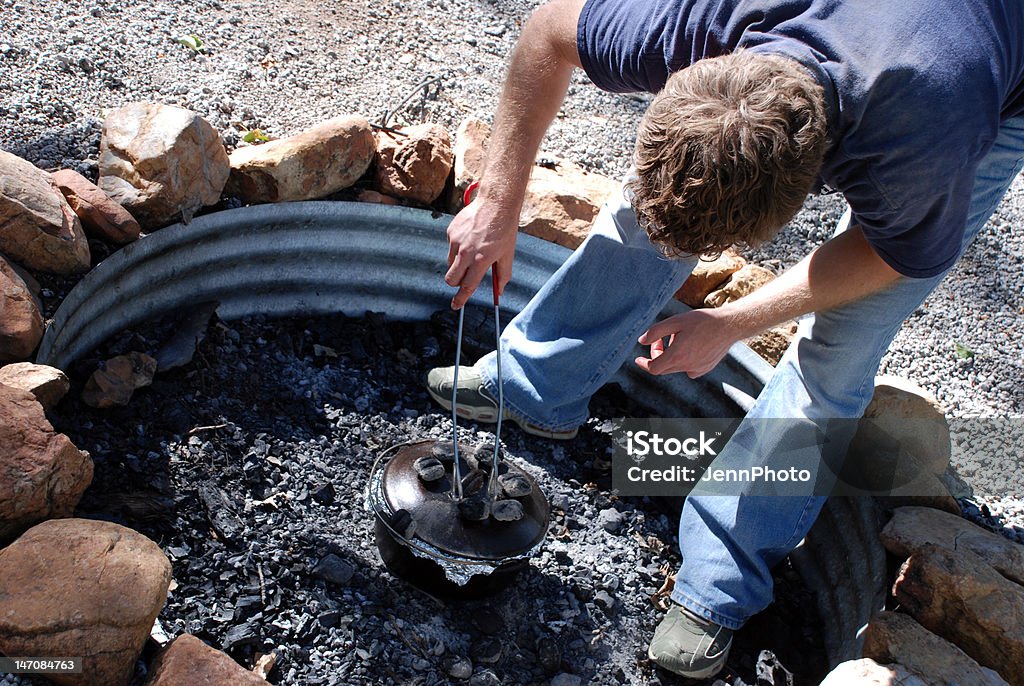 Dutch Oven Cooking A healthy young man dutch oven cooking in the firepit Adult Stock Photo