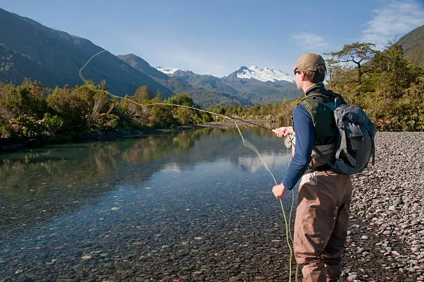 Fly fishing to wily trout on a still pool in a river high in the Patagonian Andes of Chile.