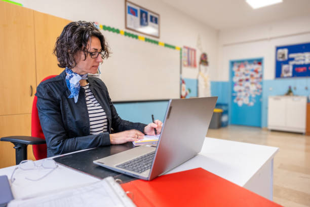 istock Woman teacher sitting and writing 1470850713