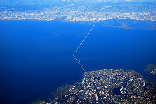 The San Mateo bridge crosses the blue water of the San Francisco Bay as seen from an airplane flight as it approaches the airport