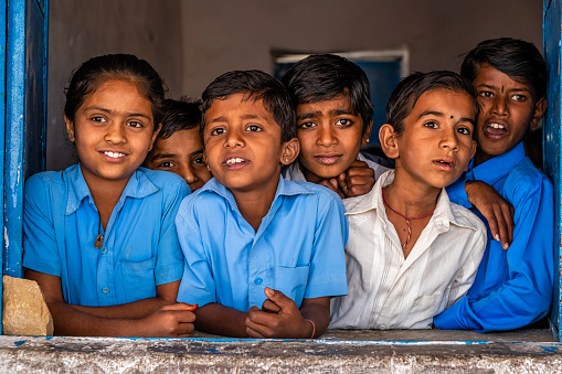 Indian school children looking outside the window from their classroom, Rajasthan, India