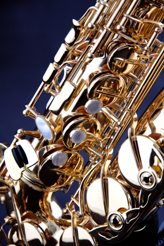 A gold saxophone isolated against a low key blue black background in the vertical format.