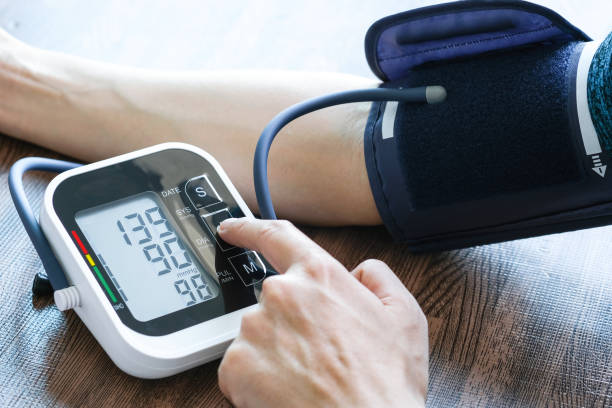 man checks blood pressure monitor and heart rate monitor with digital pressure gauge. health care and medical concept. - 血壓計 個照片及圖片檔