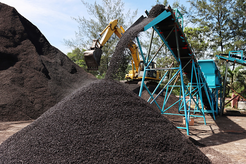 Bengkulu, Indonesia, January 18, 2023: Workers are collecting palm kernel shells using equipment and bulldozer vehicles that will be prepared for export as bio-energy feedstock