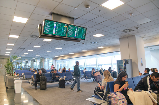 Buenos Aires, Argentina, November 18, 2022: Waiting room in the boarding area of the Jorge Newbery International Airport: passengers and information screens on flight status.