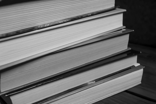 A stack of books. Photos in black and white - books stacked on top of each other - shooting up close.