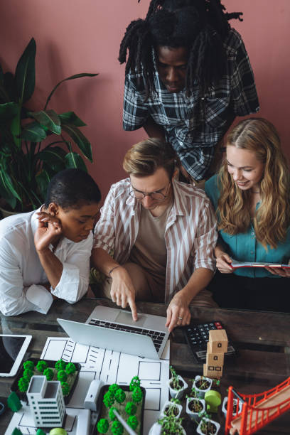 istock International diverse group of students working on modern urban architecture project with renewable green energy source, alternative electricity, waste recycling. Brainstorming ideas, business plan 1470868543