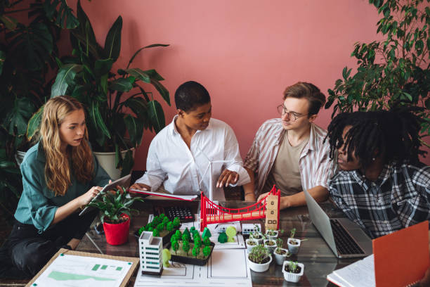 istock International diverse group of students working on modern urban architecture project with renewable green energy source, alternative electricity, waste recycling. Brainstorming ideas, business plan 1470868644