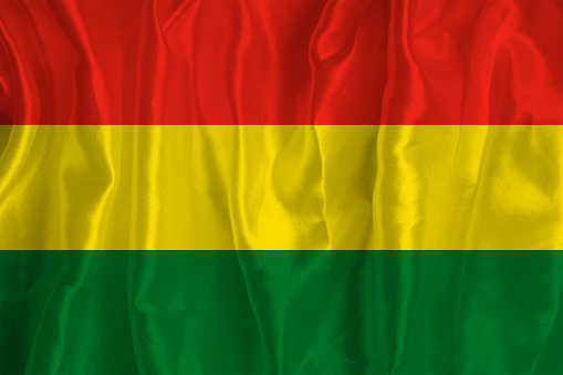 The flag of Bolivia on a silk background is a great national symbol. Fabric texture The official state symbol of the country.