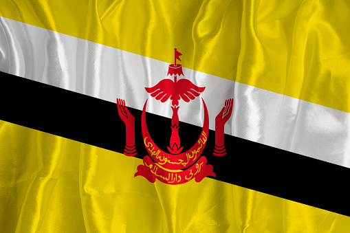 The flag of Brunei on a silk background is a great national symbol. Fabric texture The official state symbol of the country.