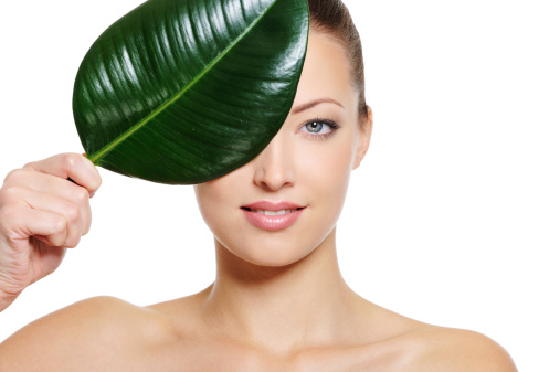 Perfect caucasian woman face covering with a fresh green leaf
