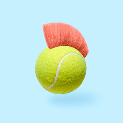 Humor pop art fun tennis ball with a pink mohawk hairstyle. Minimally fun is the concept of sports fashion and fun. High quality photo