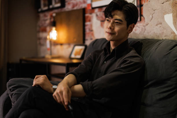 Young Asian men sitting on the sofa using mobile phones
